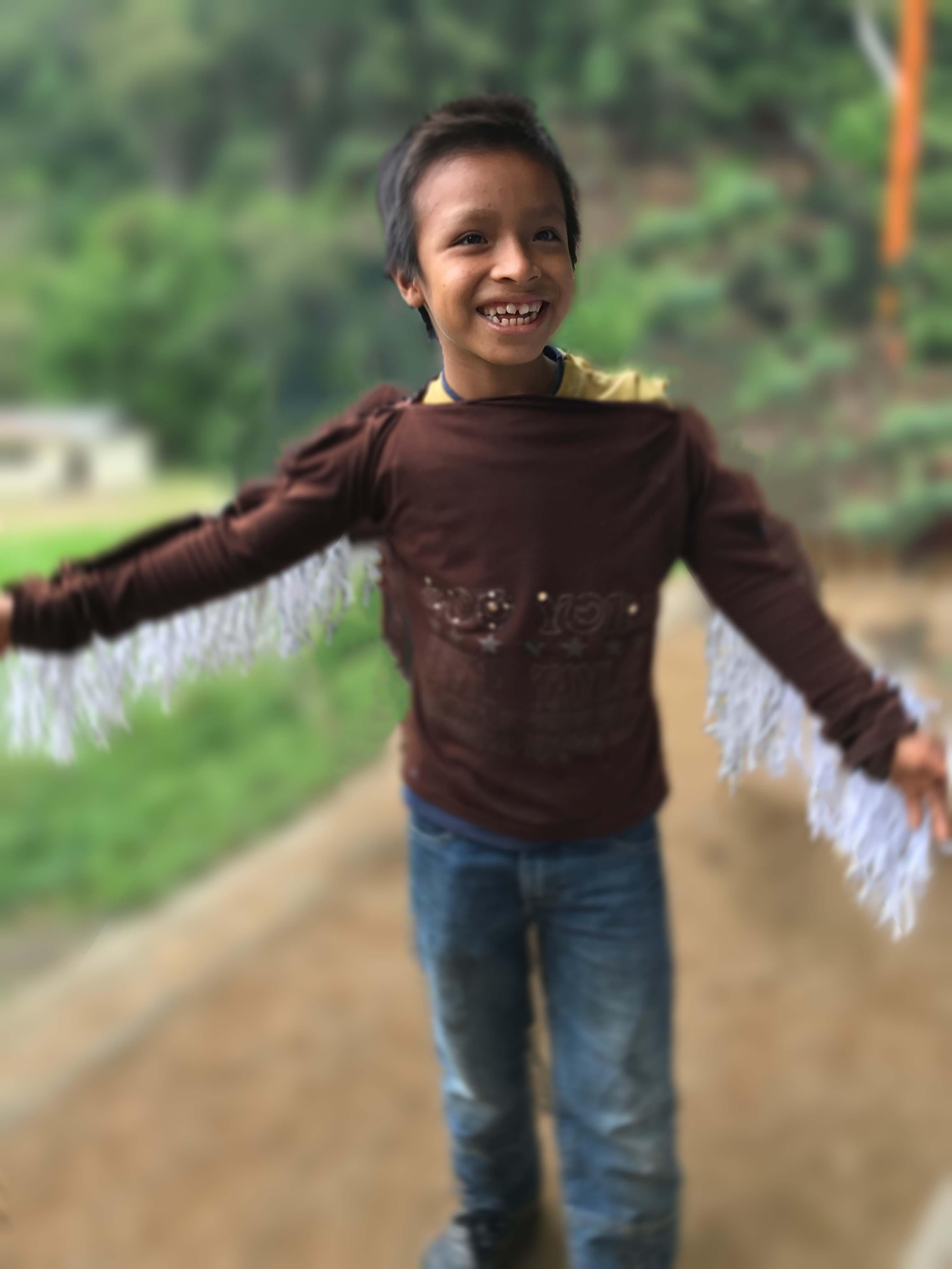 A young DAT Drama Club performer wearing paper wings.